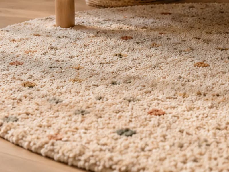 Rond, zacht vloerkleed in gebroken wit met kleine gekleurde bloemetjes