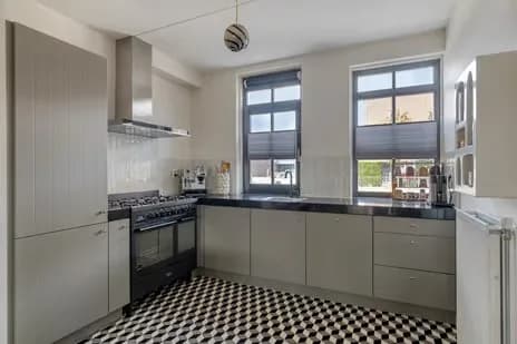 Een gewone grijze keuken met een zwart-wit geblokte vloer
